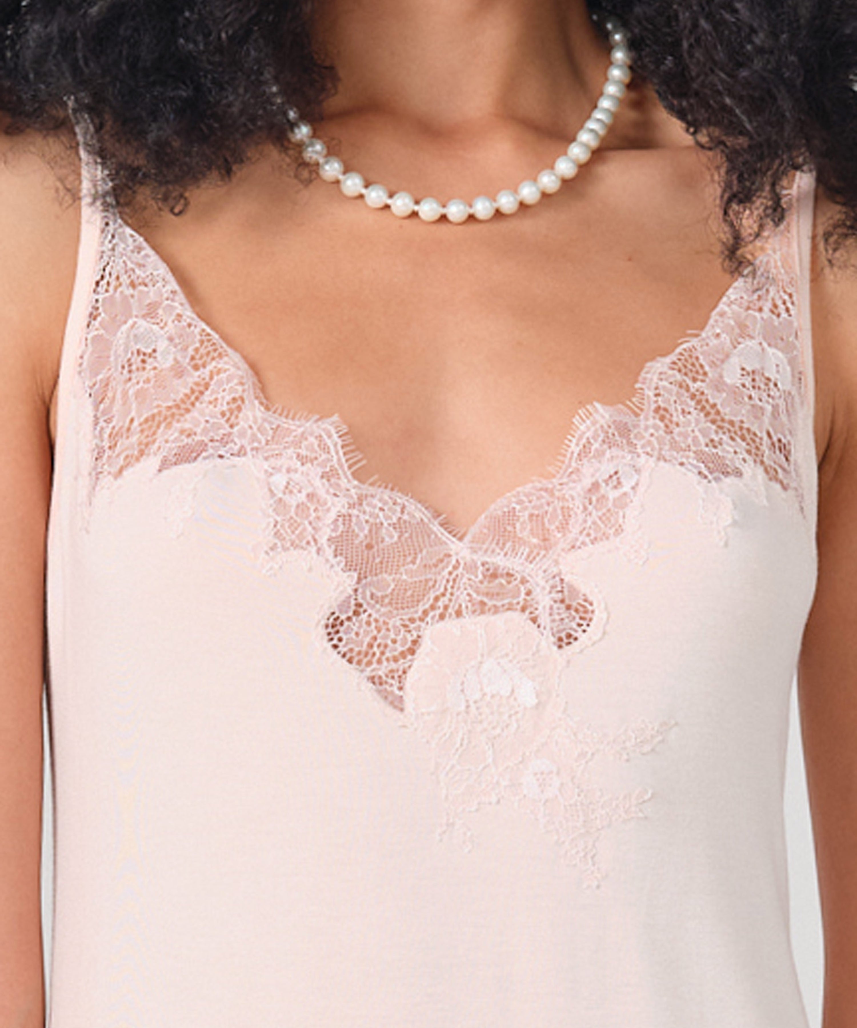 Effetto bamboo chemise spaghetti strap 03162 – women's sleepwear, rosy peach
Close-up of a person wearing a lace-trimmed top and pearl necklace.