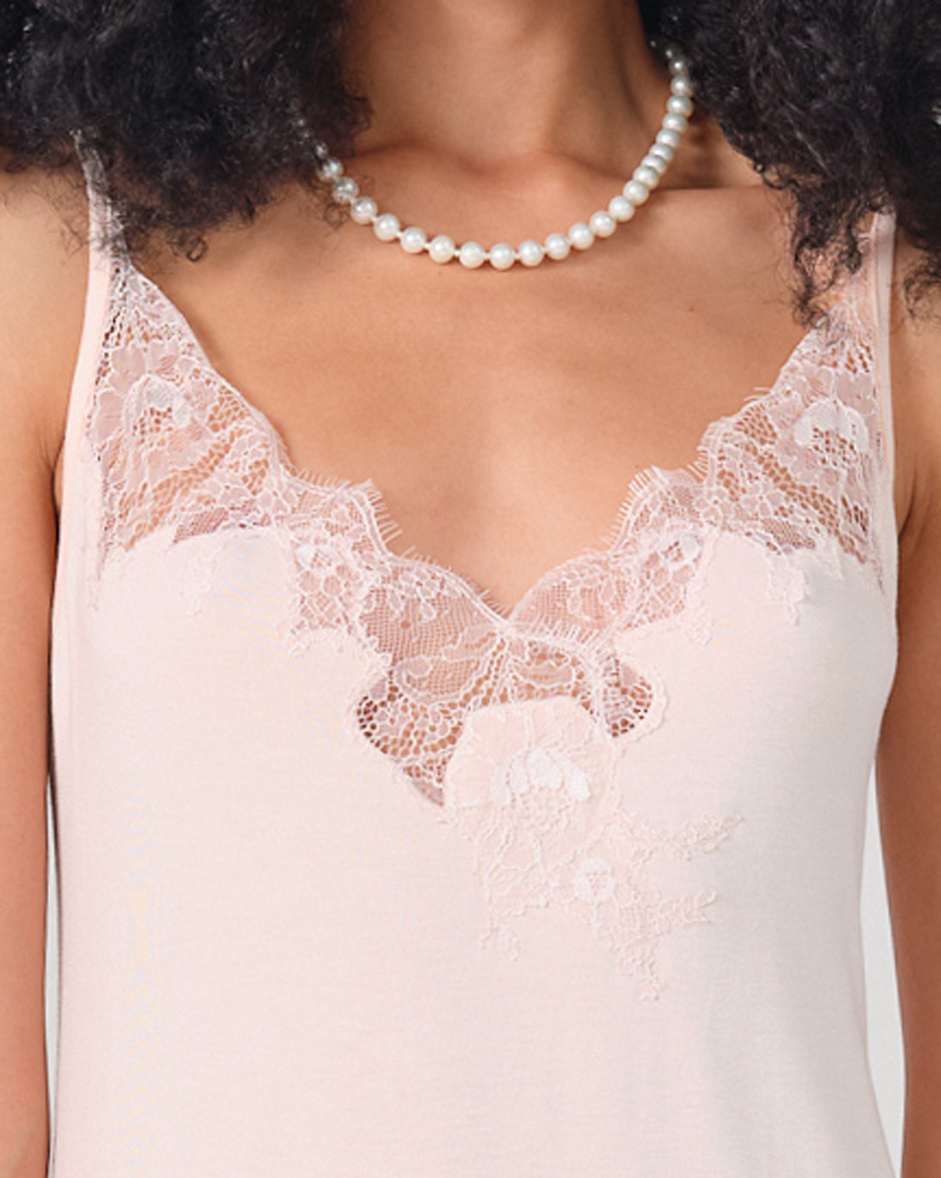 Effetto bamboo chemise spaghetti strap 03162 – women's sleepwear, rosy peach
Close-up of a person wearing a lace-trimmed top and pearl necklace.